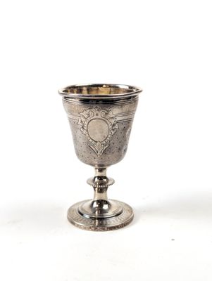 une coupe ancienne en argent posée sur une surface blanche, avec un fond blanc
