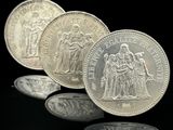 trois pièces d'argent empilées les unes sur les autres sur une surface noire