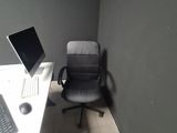 a desk with a computer and a chair in the corner