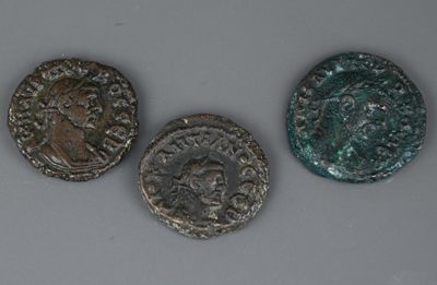 trois pièces romaines, dont l'une représente la tête d'un homme et l'autre celle d'un