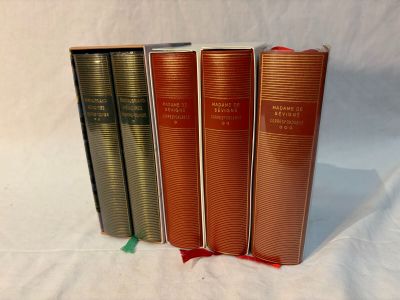 three books are lined up on a white surface with a green ribbon