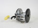 a close up of a reel on a white surface with a yellow handle