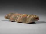un vieil objet en pierre sur le dos duquel figure une tête de poisson