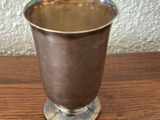 a silver cup on a wooden table with a white wall in the background