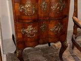 a wooden chest of drawers next to a chair in a room