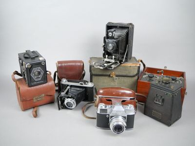 beaucoup de vieux appareils photo et de valises posés sur une table