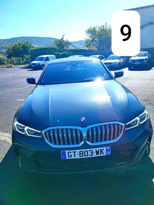 une BMW noire garée sur un parking, avec une plaque d'immatriculation