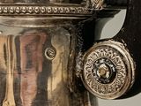 a silver tea pot with a handle on a table