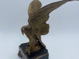 statue of a winged bird on a stand with a blue base
