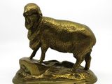 statue en bronze représentant un mouton debout sur un rocher, sur fond blanc