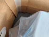 a white toilet in a box with a plastic cover on it
