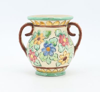 a vase that has a handle on it with flowers on it