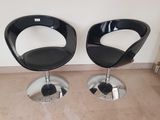 une paire de fauteuils en cuir noir avec une structure et des pieds chromés