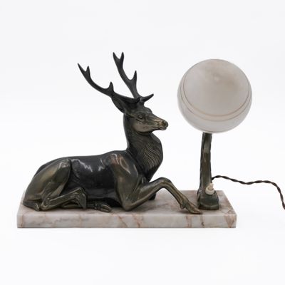 a statue of a stag sitting on a marble base with a lamp on it