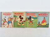 three mickey mouse books are lined up on a white surface