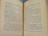 someone is holding an open book in their hand on a table