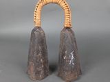 paire de cloches anciennes en bois avec une poignée en osier sur fond gris