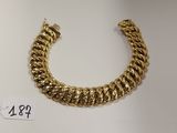 gros plan d'un bracelet en or sur une surface blanche