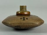 a brown vase with writing on it sitting on a table