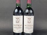 two bottles of red wine sitting next to each other on a table