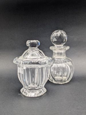 deux bocaux en verre transparent avec leurs couvercles, posés sur une surface noire