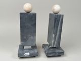 pair of marble sculptures with marble balls on stands on a white background