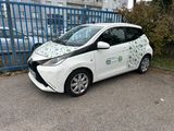 une petite voiture blanche garée devant une clôture bleue