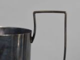 a metal cup with a handle on a table