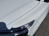 a white car parked in a parking lot with a shadow of a person