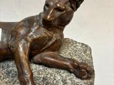 a bronze statue of a dog laying on a rock