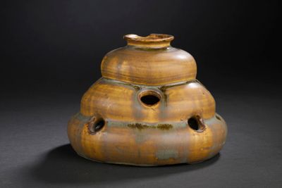 a brown vase with holes in it on a black background