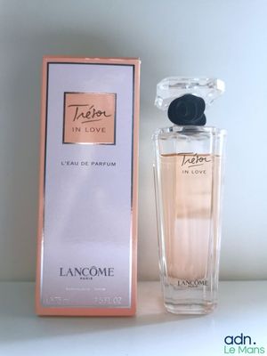 une photo représentant un flacon de parfum posé à côté d'une boîte sur une table