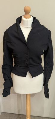 un mannequin vêtu d'une veste noire, posé sur un pied de mannequin