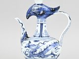 a blue and white vase with a bird on top of it