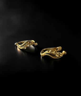 a pair of gold and pearl earrings on a black surface