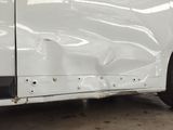 a white car that has been dented and is parked in a garage