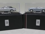 pair of silver model cars in display cases on black bases