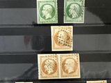 Plusieurs timbres différents sont exposés dans une vitrine posée sur une table.