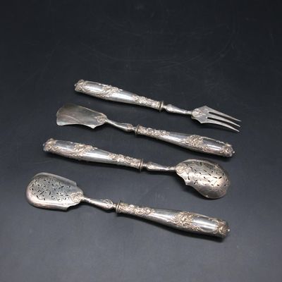 four pieces of silverware on a table with a black background