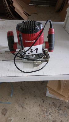 une ponceuse électrique rouge et noire posée sur une table blanche