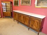 une grande armoire en bois dans une pièce où sont accrochés des tableaux aux murs