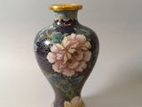 a small vase with flowers on it on a white surface