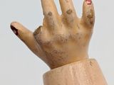 a wooden hand that is holding something in it ' s right hand