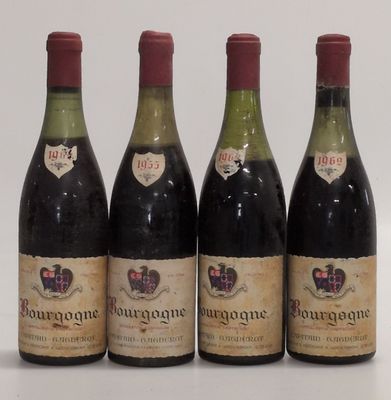 four bottles of wine are lined up in a row on a white surface