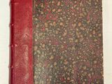 un vieux livre à la couverture rouge posé sur une table blanche