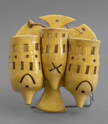 three yellow vases sitting on a metal stand with faces painted on them