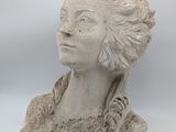 sculpture of a woman ' s head on a rock with a white background