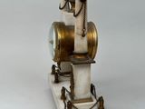 a clock that is sitting on a stand on a white surface