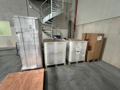 de nombreuses caisses et palettes dans un entrepôt équipé d'un escalier en colimaçon