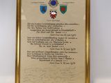 une image représentant une photo encadrée d'une plaque sur laquelle figure un blason